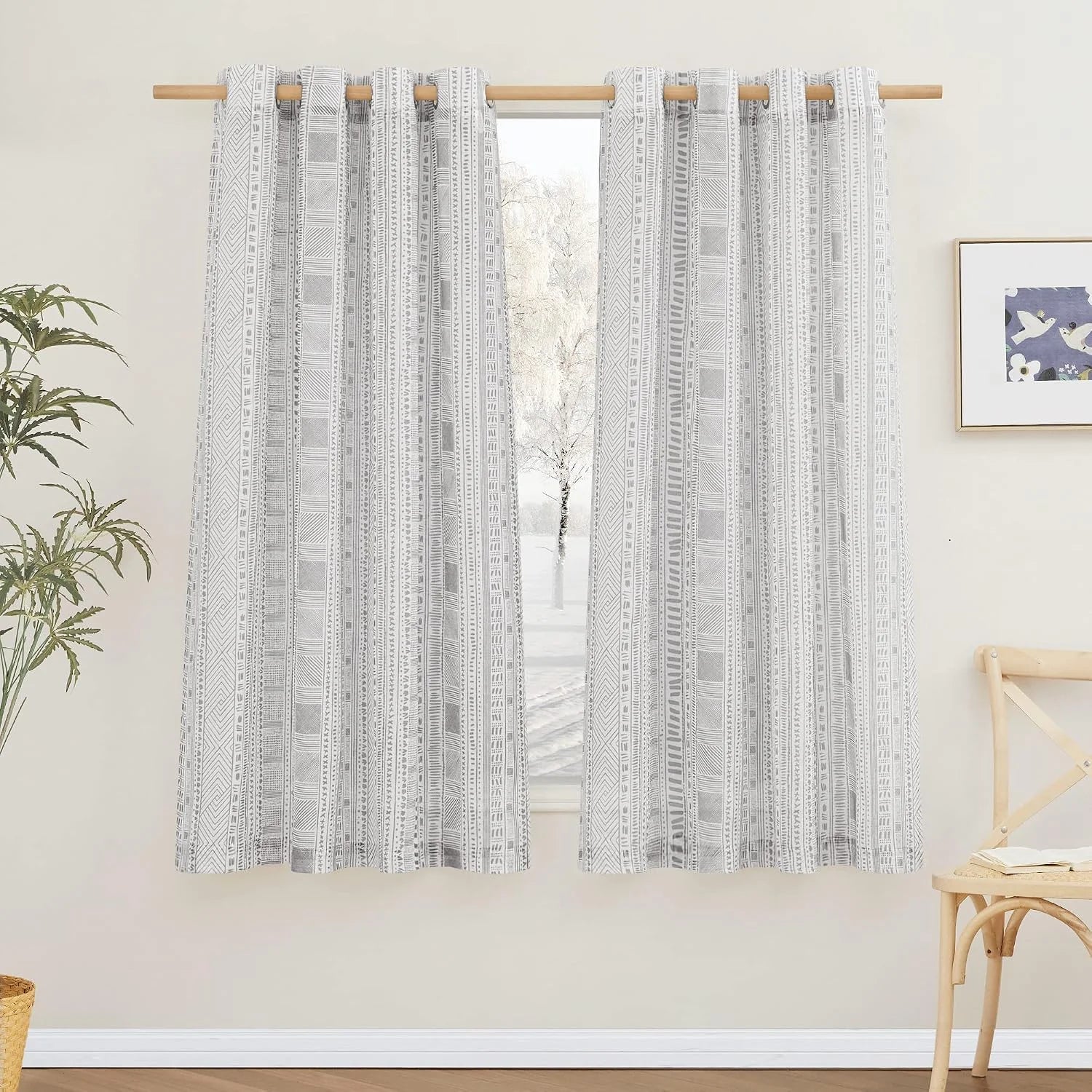 Light gray geometric patterned curtains on a natural wood rod in a bright room