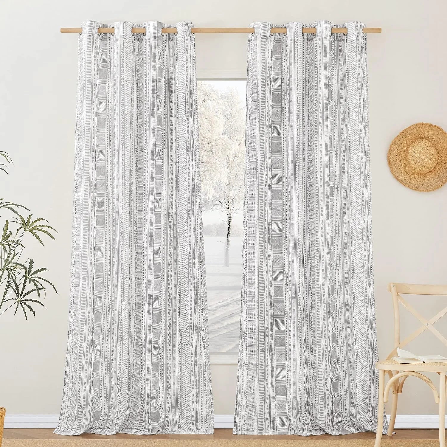 Gray and white geometric sheer curtains with grommet top on a light wood rod