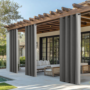 Dark gray outdoor curtains with grommet tops hanging from a wooden pergola on a sunny patio.
