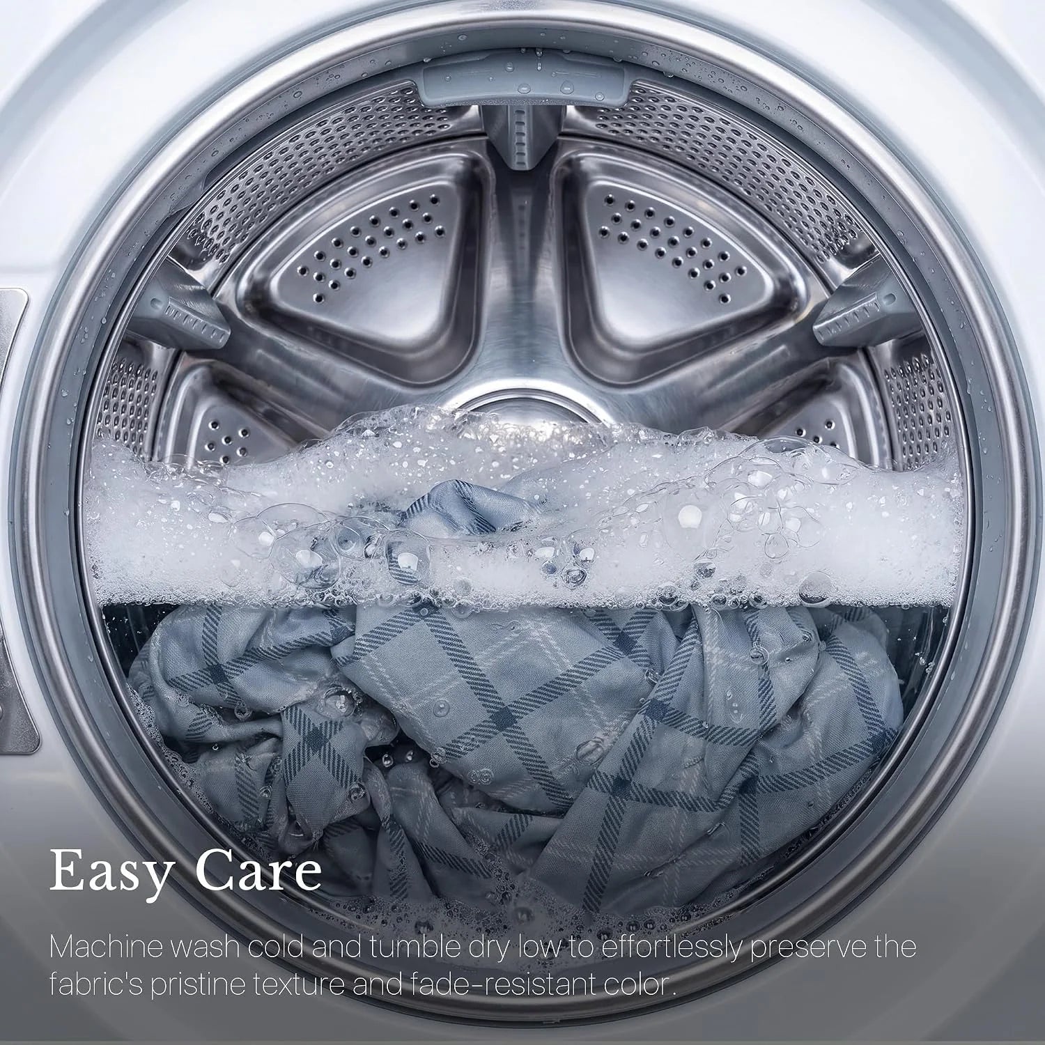 Gray plaid fabric washing in a front-load machine with soap bubbles and easy care text