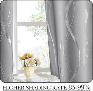 Gray window curtains with shimmering silver wavy pattern hanging against a bright window.