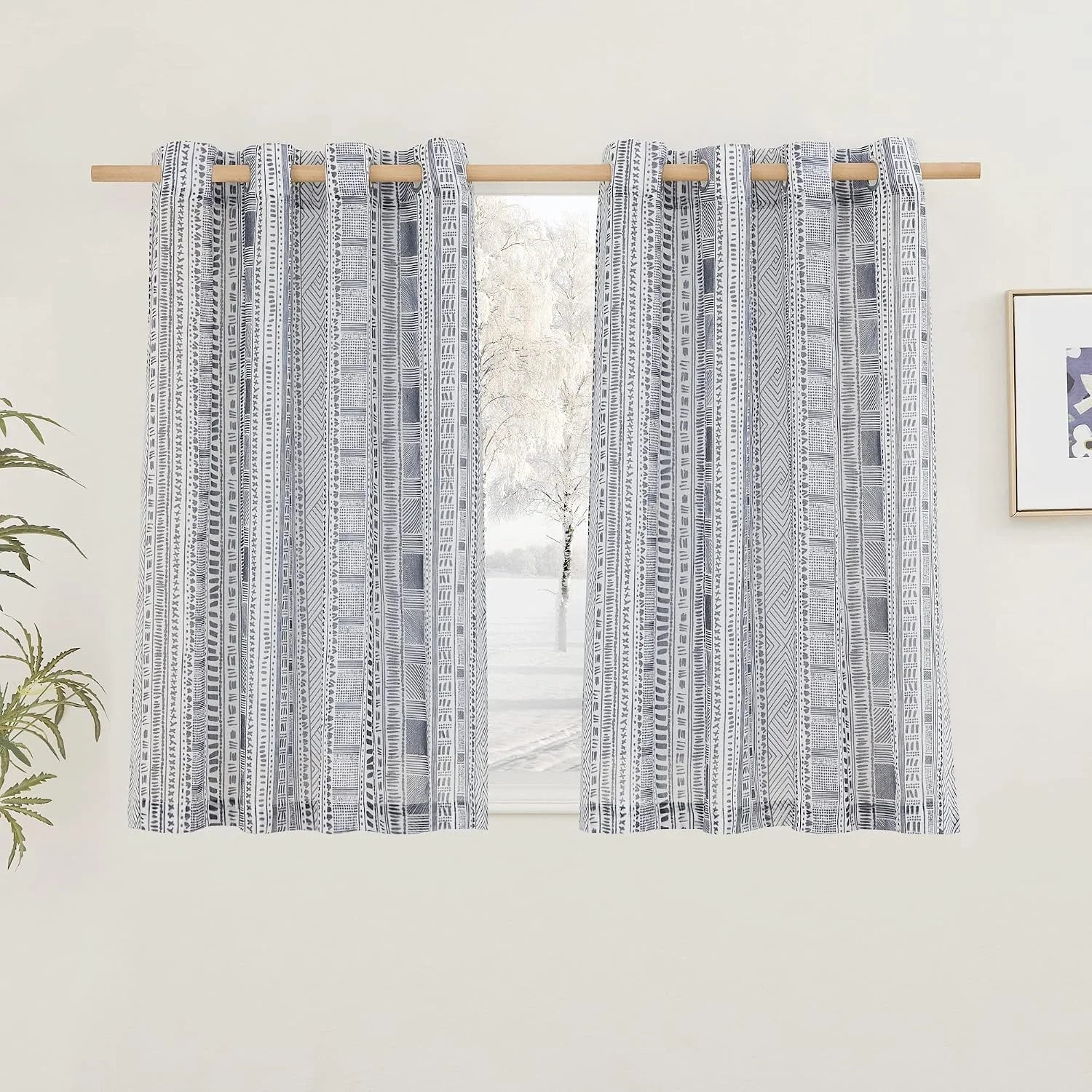 Gray and white tribal print rod pocket curtains hanging on a wooden curtain rod
