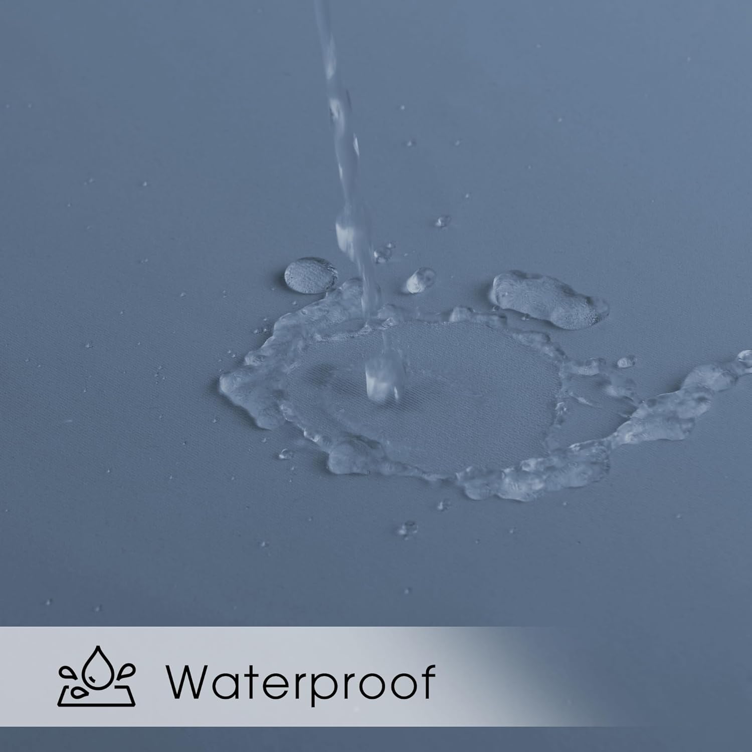 Close-up of water beading and rolling off a smooth gray waterproof fabric surface, demonstrating its liquid resistance.