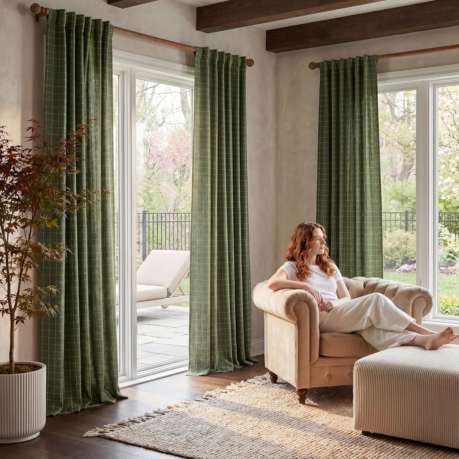 Green checked pattern curtains in a cozy living room with a woman relaxing in a beige armchair by the window.