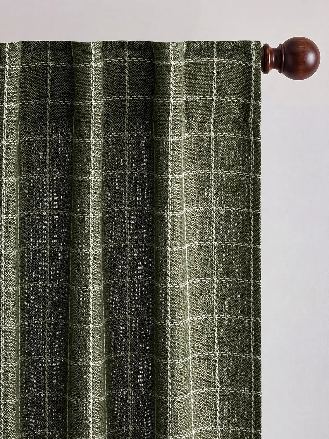Dark green plaid curtain panel with white checks on a wooden rod