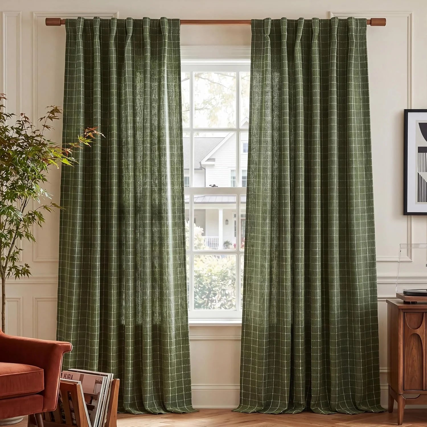 Green plaid linen-blend curtains hanging on a wooden rod in a sunlit living room with a house visible outside.