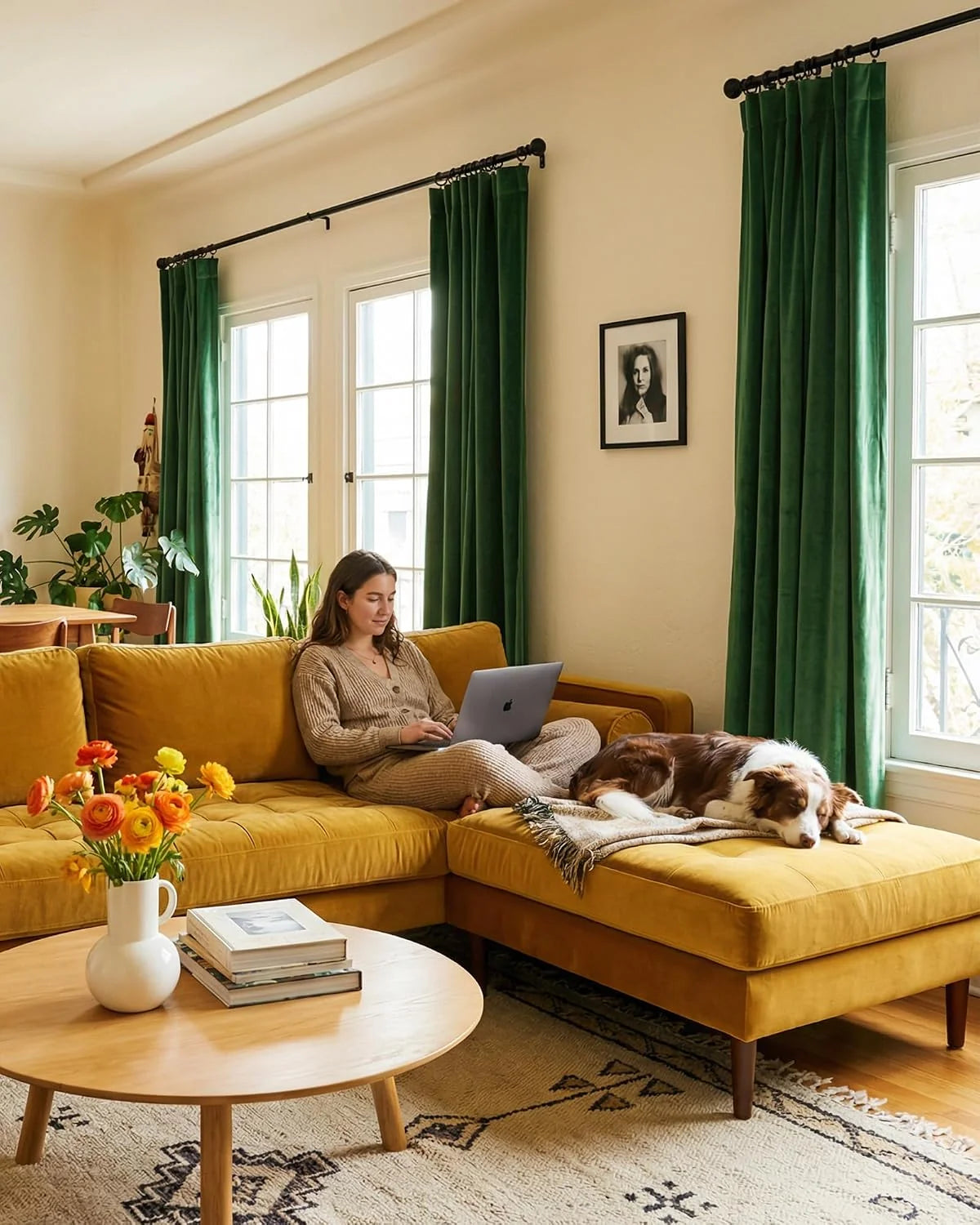 Green velvet curtains frame bright windows above a mustard sectional in a cozy living room