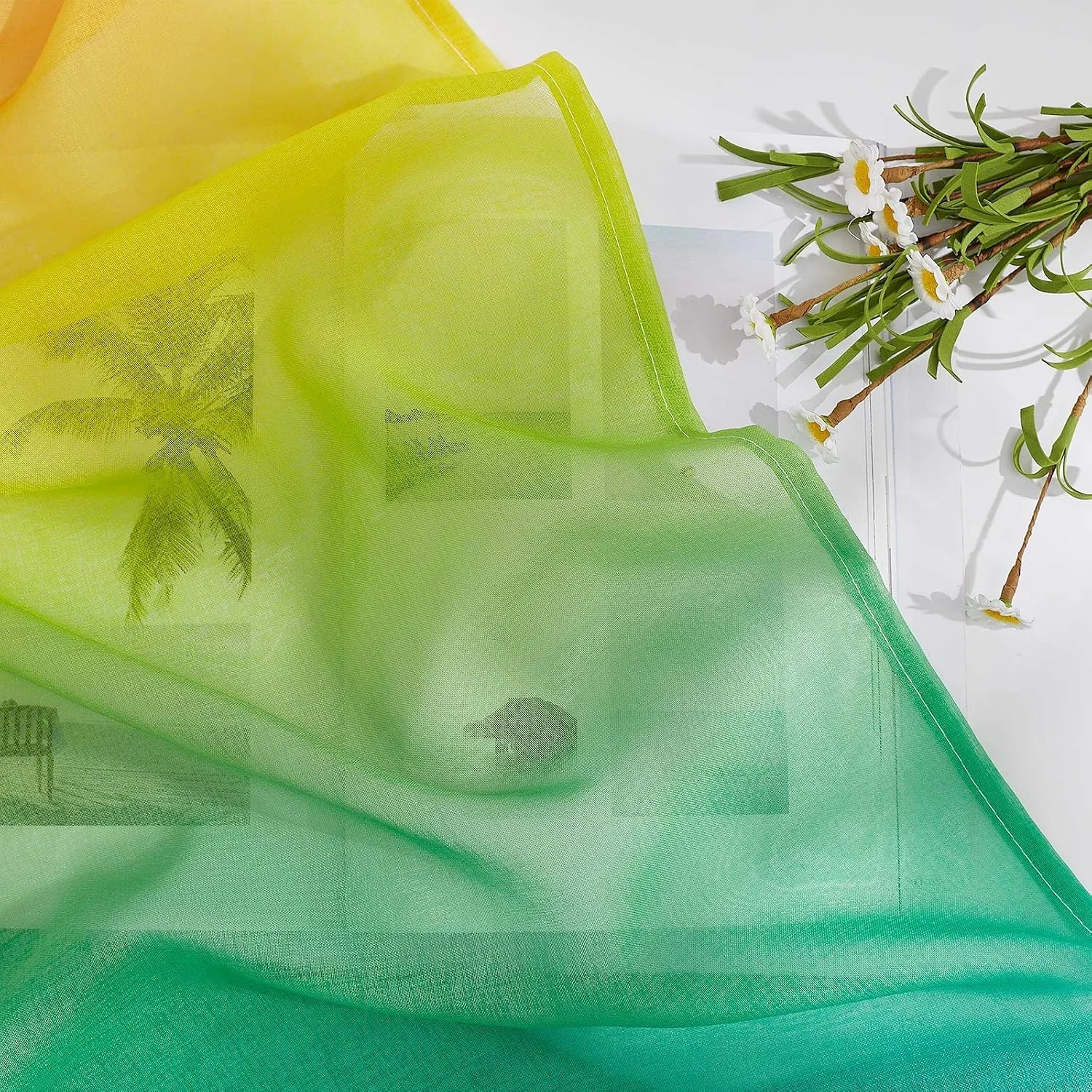 Green and yellow ombre sheer curtain fabric draped in soft folds with floral styling