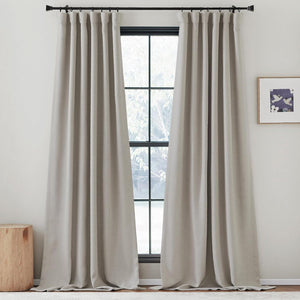 Two greige textured linen-blend pleated curtains hanging from a black rod, framing a large window.