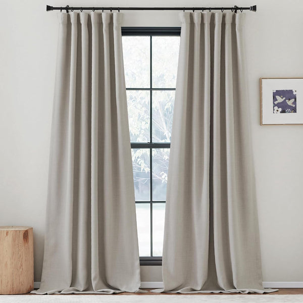 Two greige textured linen-blend pleated curtains hanging from a black rod, framing a large window.