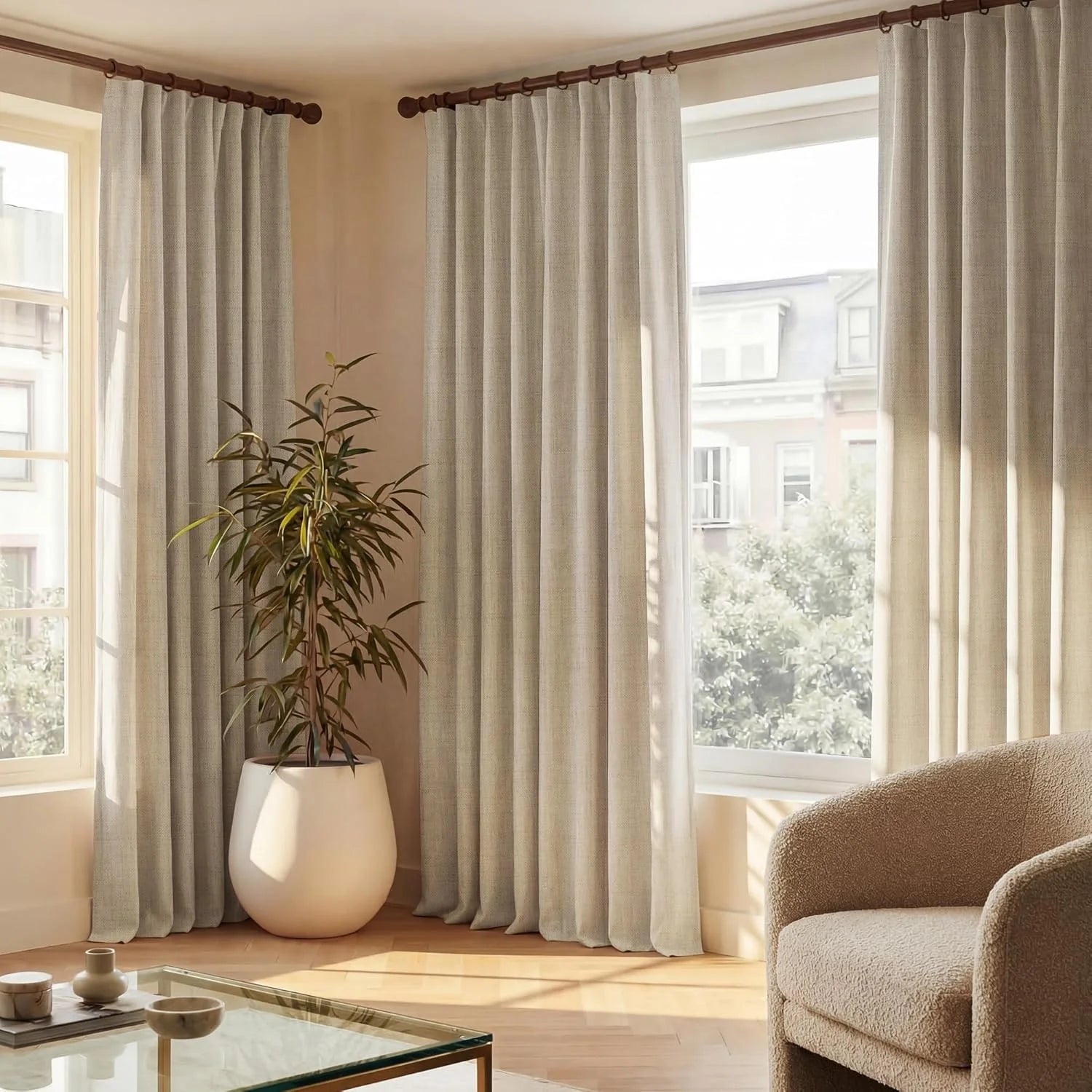 Light greige pinch pleat curtains on dark wooden rods in a bright modern living room.