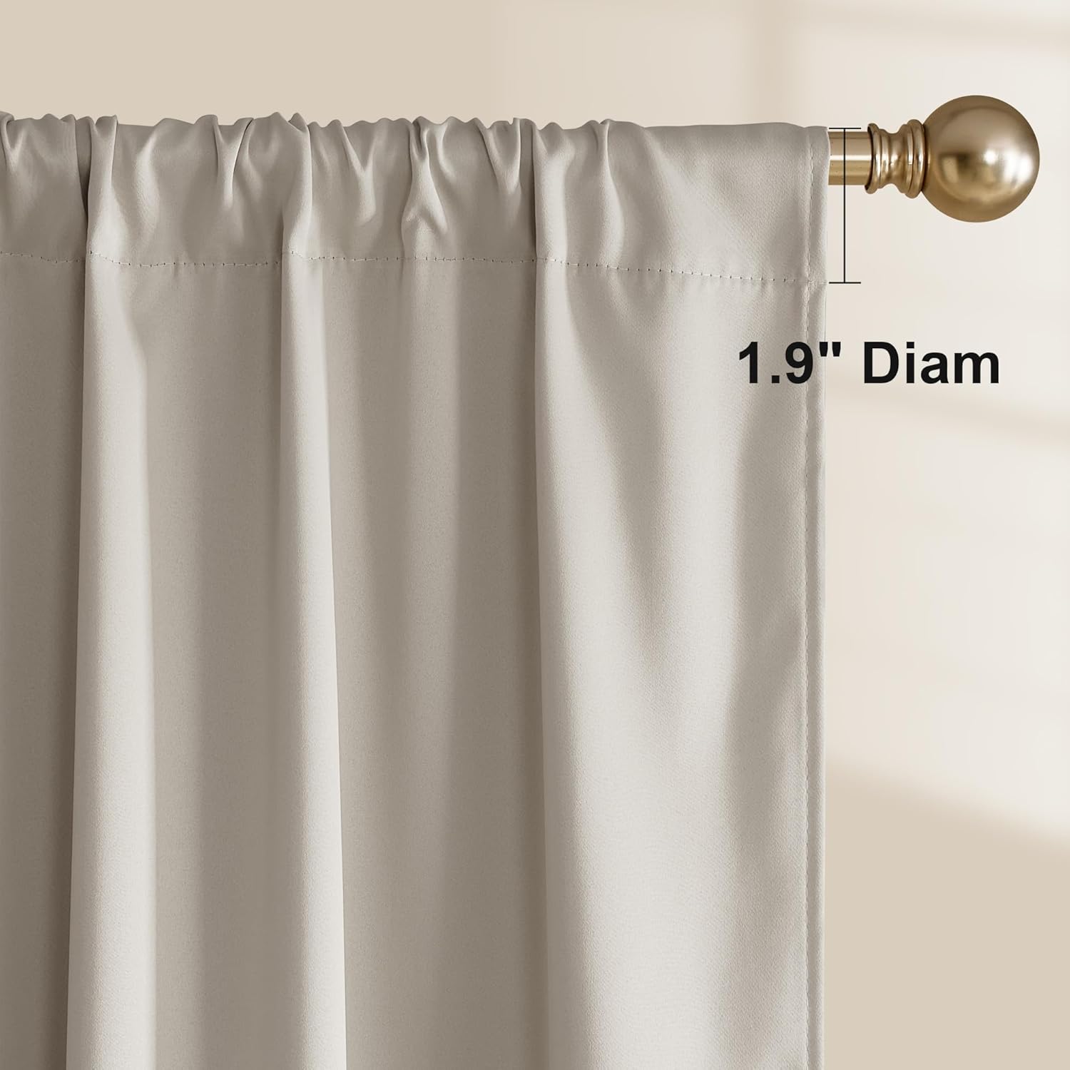 Close-up of a greige room darkening rod pocket curtain panel gathered on a decorative gold rod.