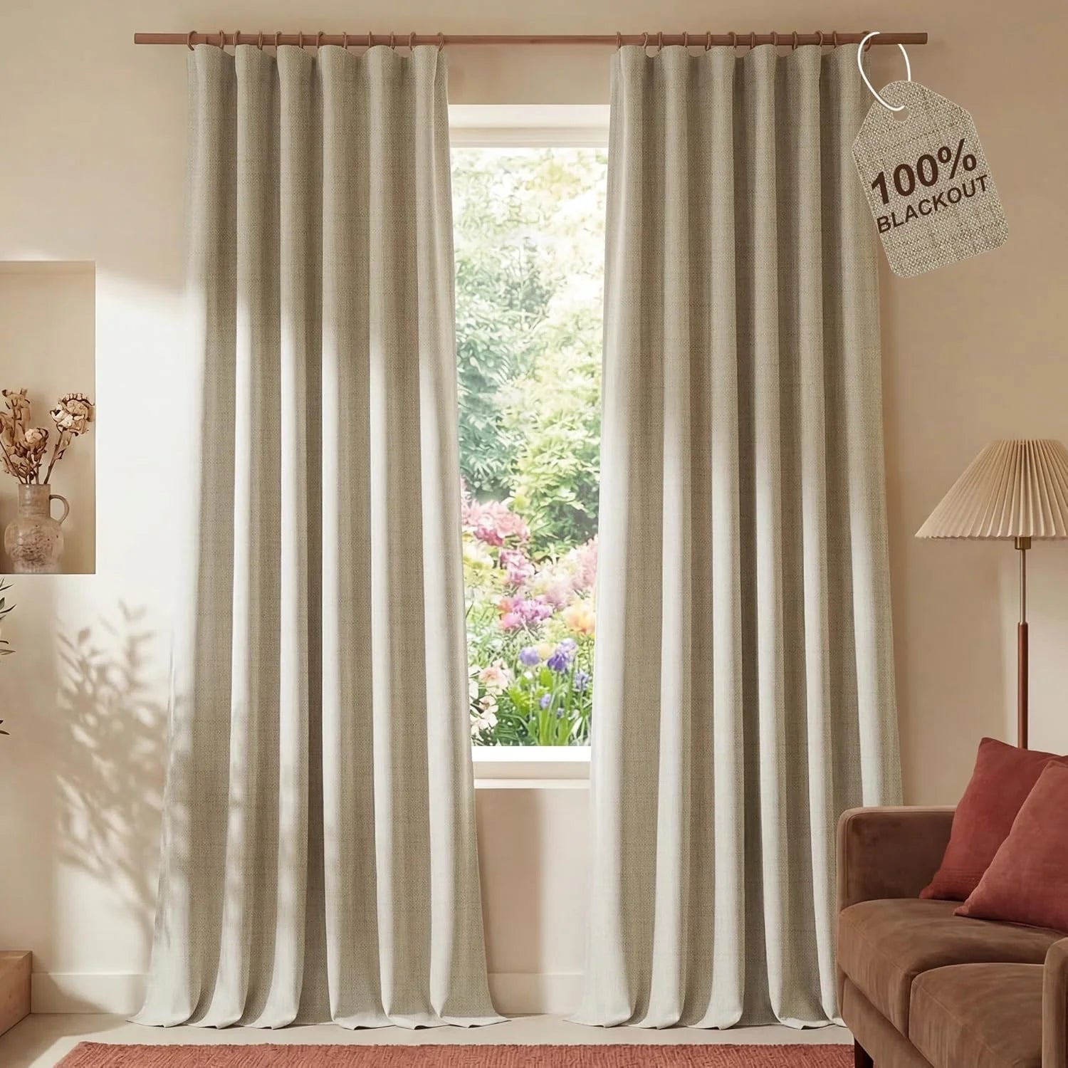 Greige textured 100% blackout curtains on a wooden rod in a cozy living room with a garden view.