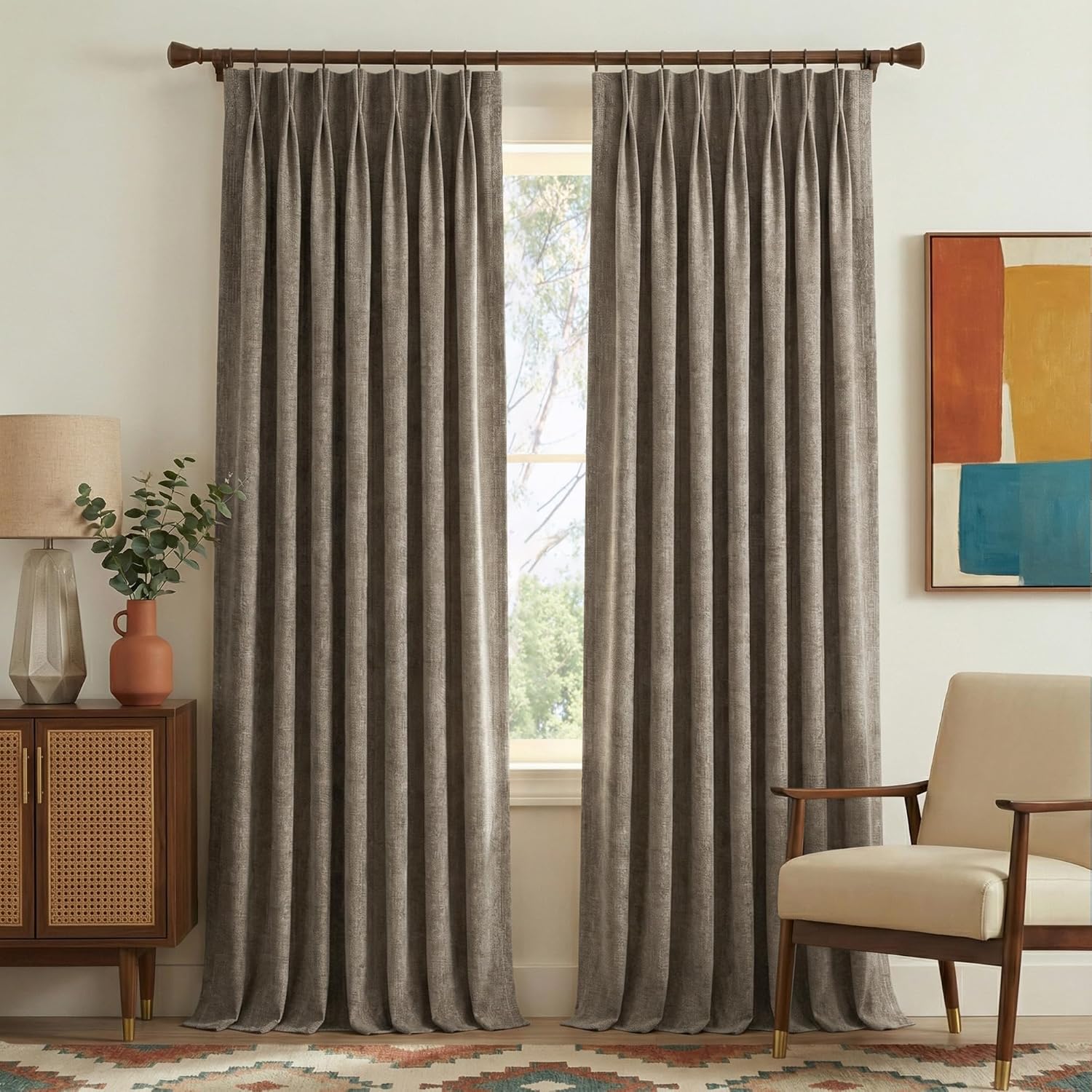 Full-length greige textured pinch pleat curtains hanging on a dark wood rod in a modern living room.