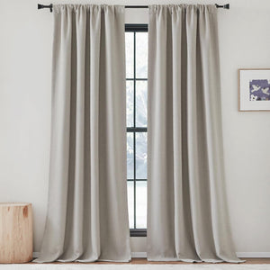 Pair of textured greige rod pocket curtains hanging on a black rod, framing a window.