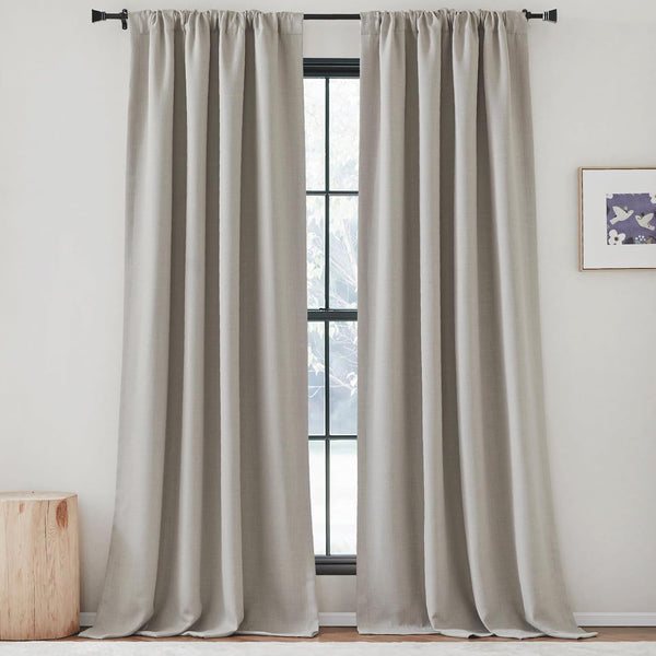 Pair of textured greige rod pocket curtains hanging on a black rod, framing a window.