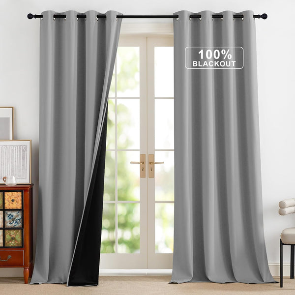 Pair of grey grommet blackout curtains with black thermal lining, hanging on a rod over glass doors.