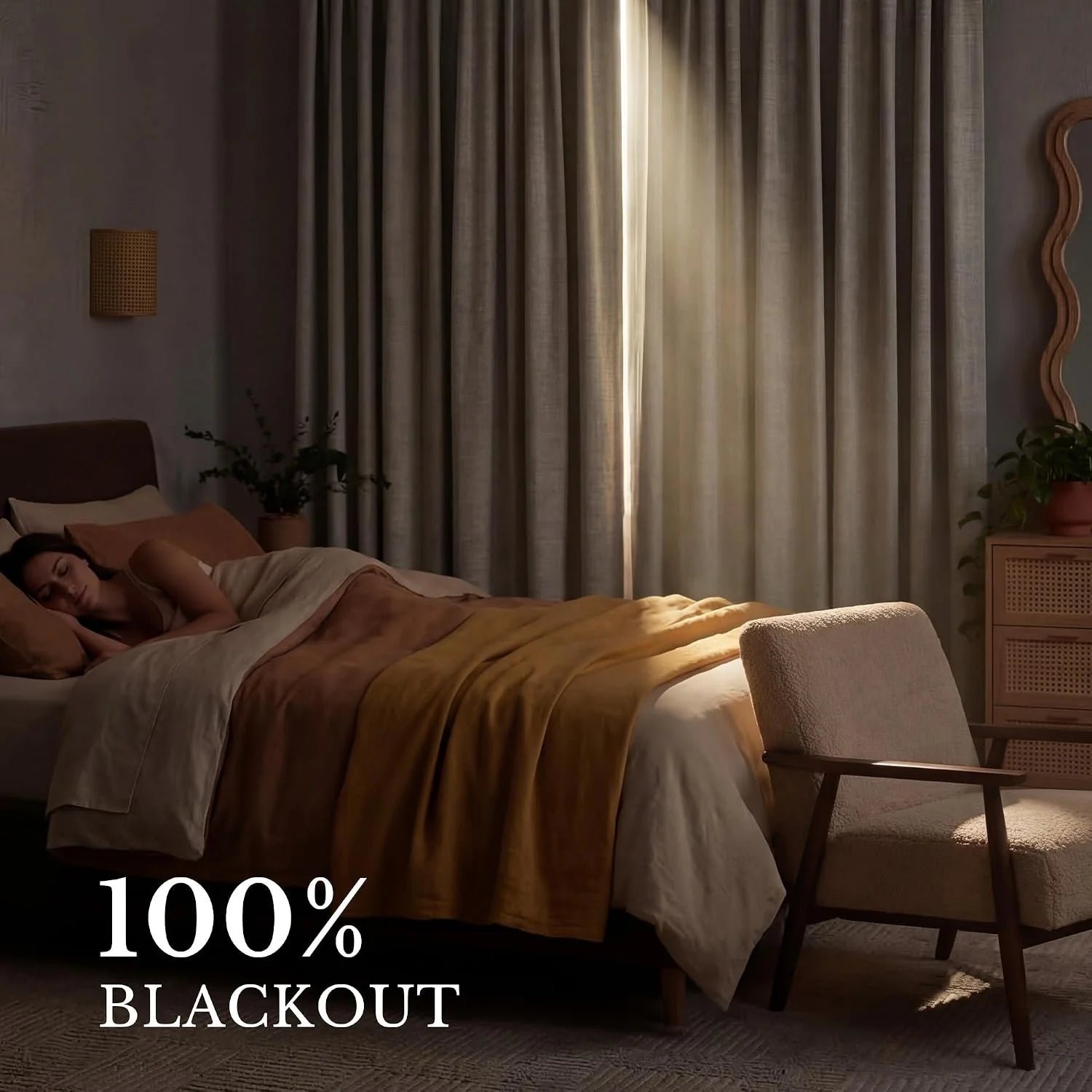 Grey blackout curtains with a bright light sliver in a dark bedroom where a woman sleeps on a cozy bed.