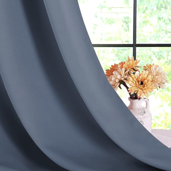 Draped grey-blue textured curtain panel, partially open, with a window and vase of peach flowers in the background.