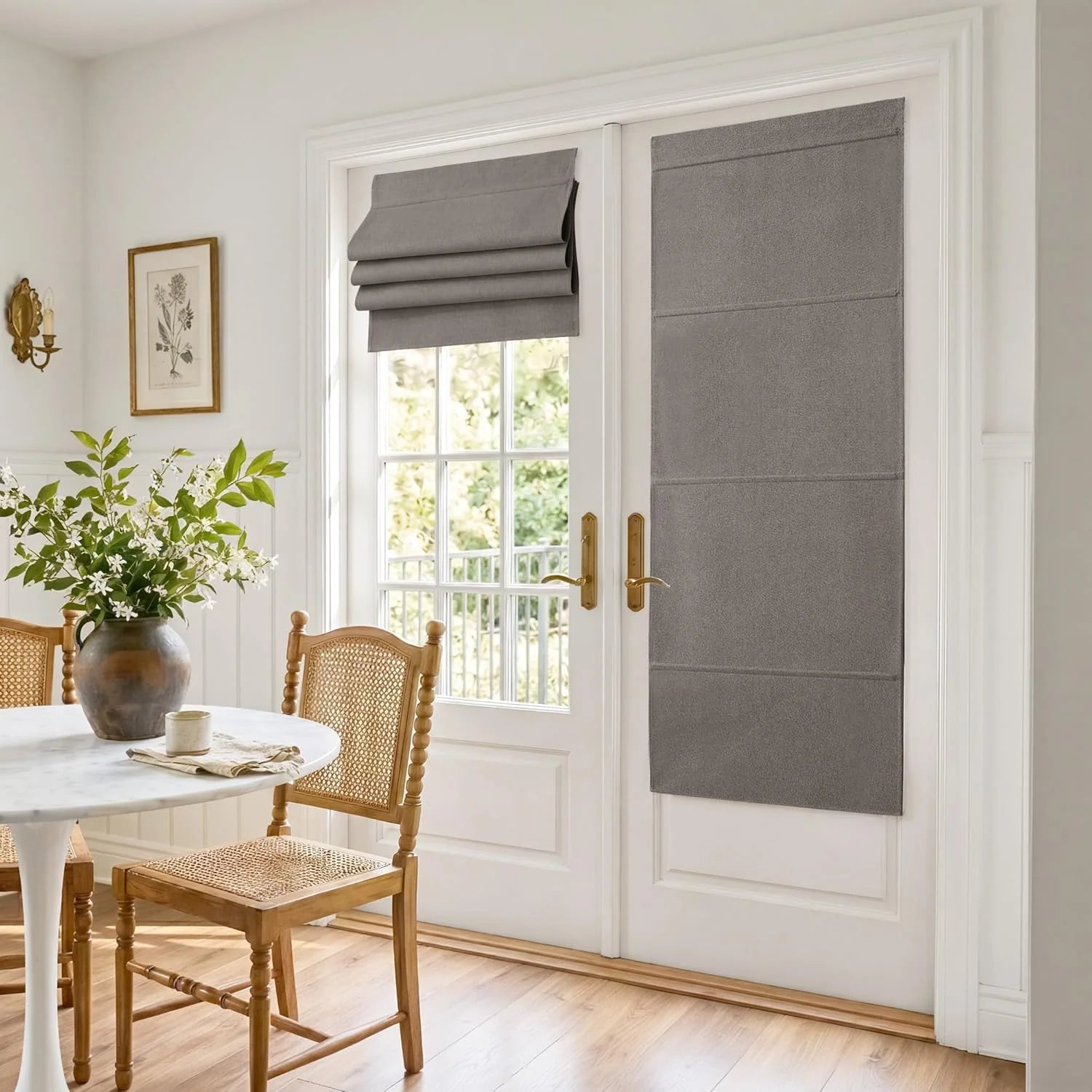 Grey flat roman shades covering white French doors in a bright dining room