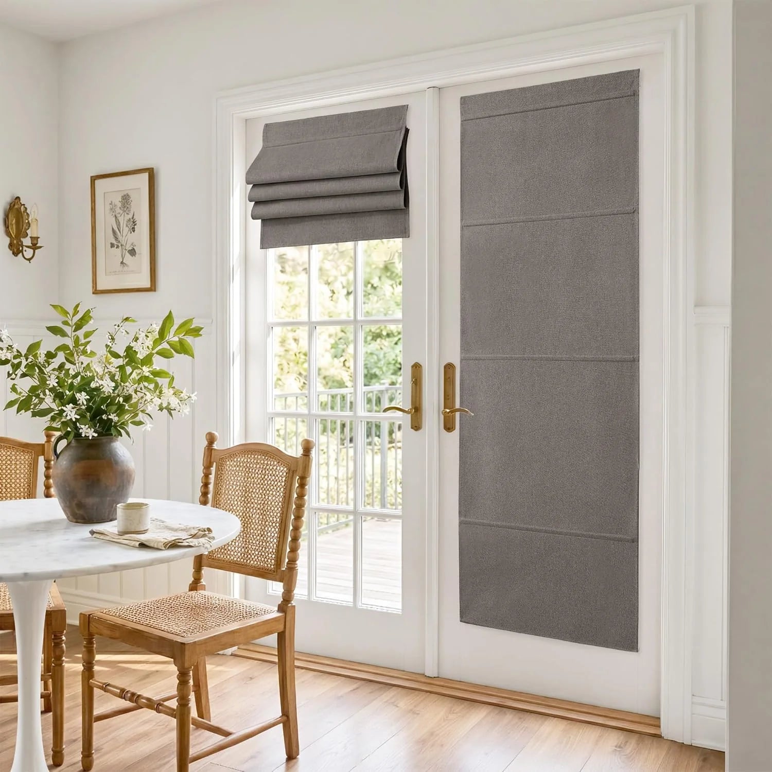 Grey fabric shades on white French doors in a bright dining room with cane chairs