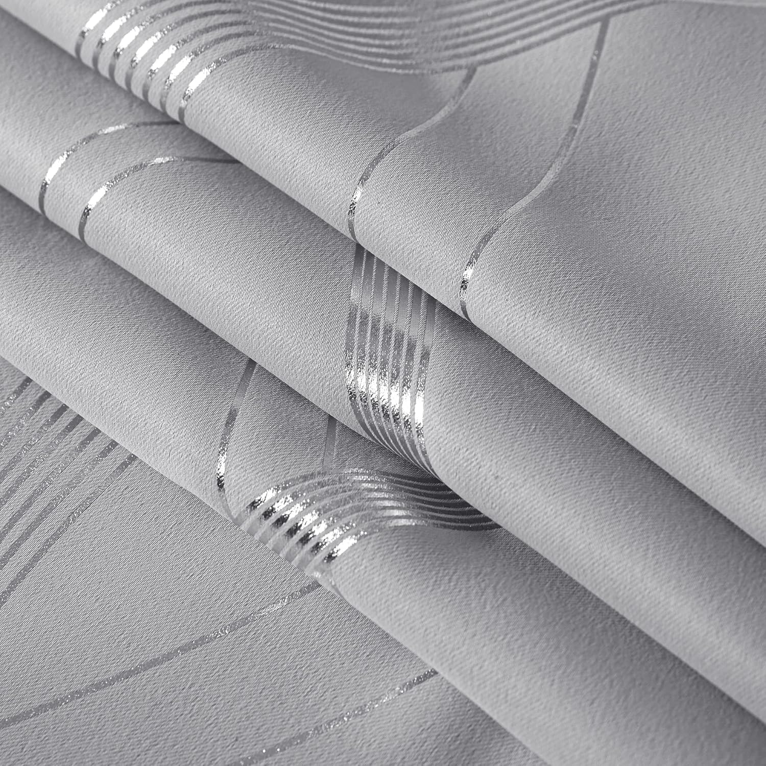 Close-up of textured light grey fabric with shimmering silver metallic wavy and striped geometric pattern.
