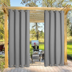 Two dark grey outdoor privacy curtains with silver grommet tops hanging on a wooden pergola.