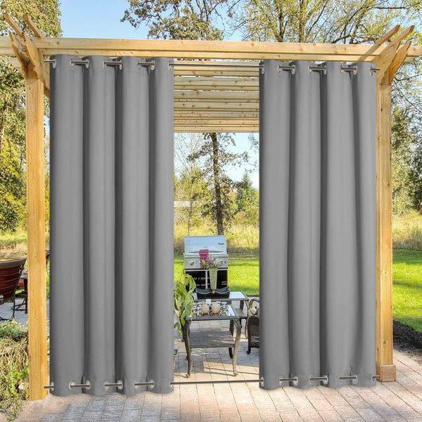 Two dark grey outdoor privacy curtains with silver grommet tops hanging on a wooden pergola.