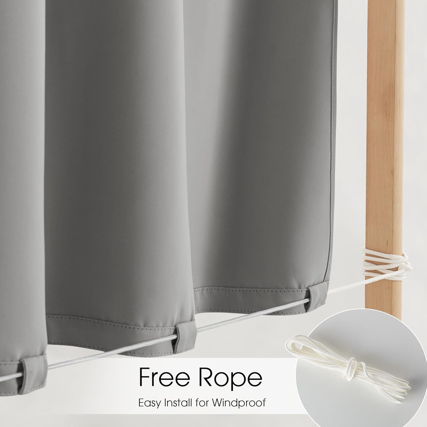 Grey outdoor curtains with windproof rope threaded through bottom loops, secured to a wooden post.