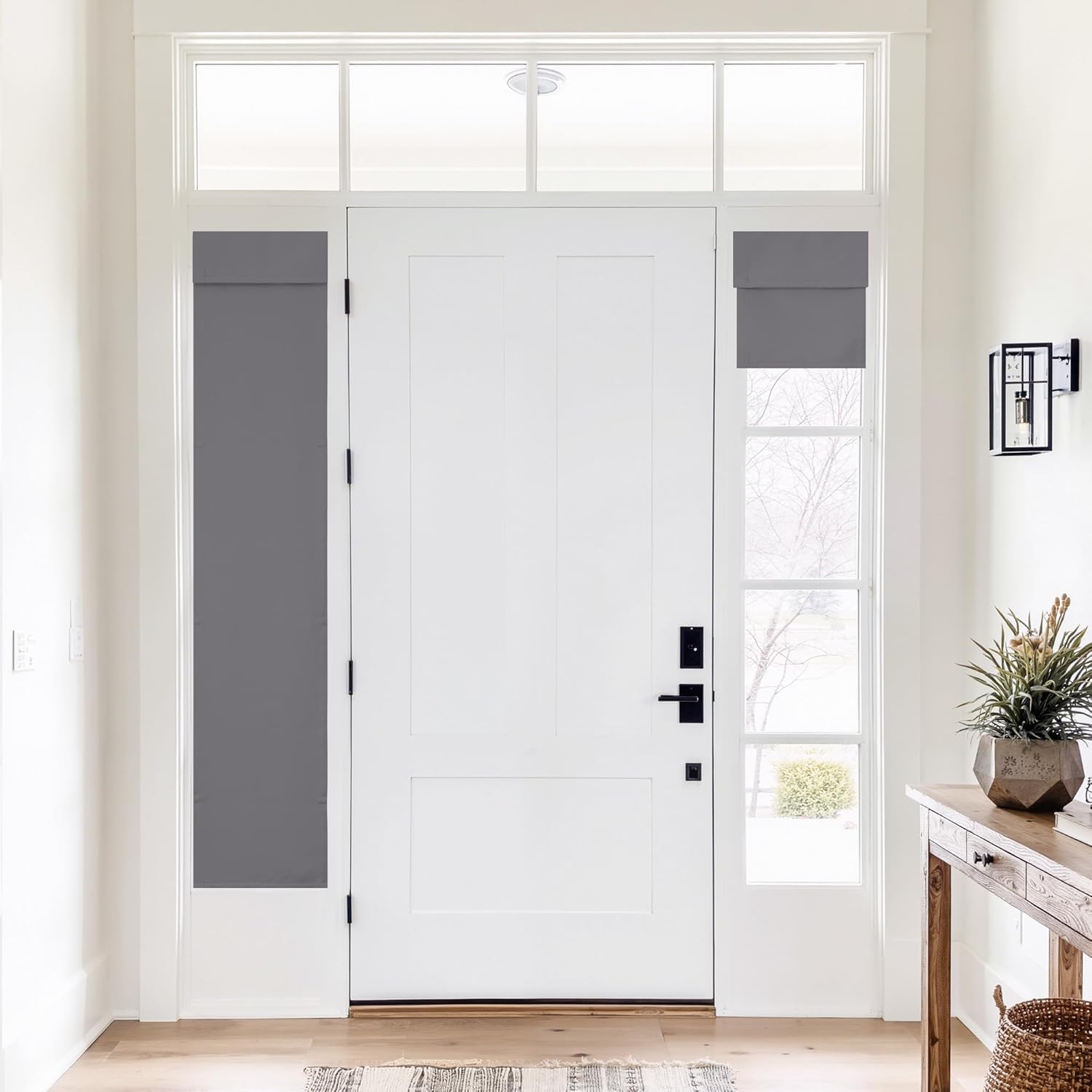 Grey fabric privacy shades on a white front door's sidelight windows. One is extended, the other rolled up.