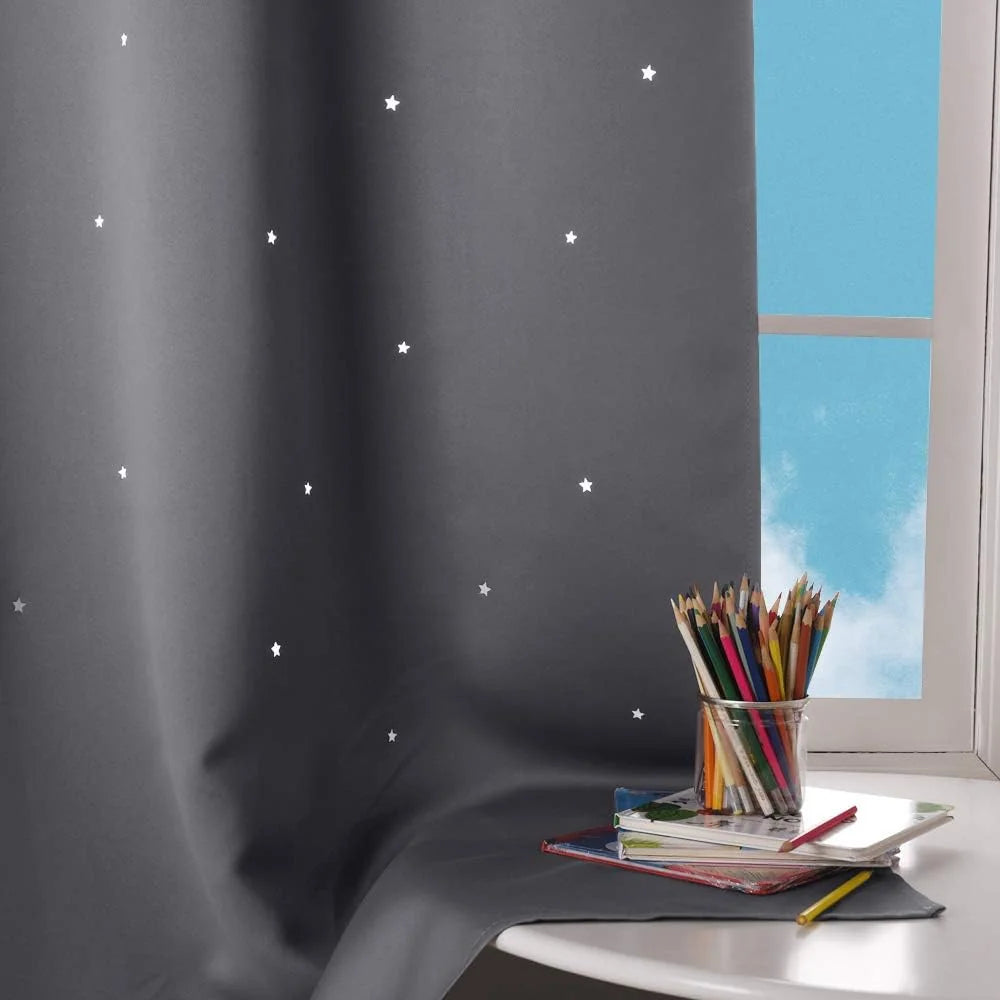 Grey blackout curtain with white stars beside a kids room window and desk