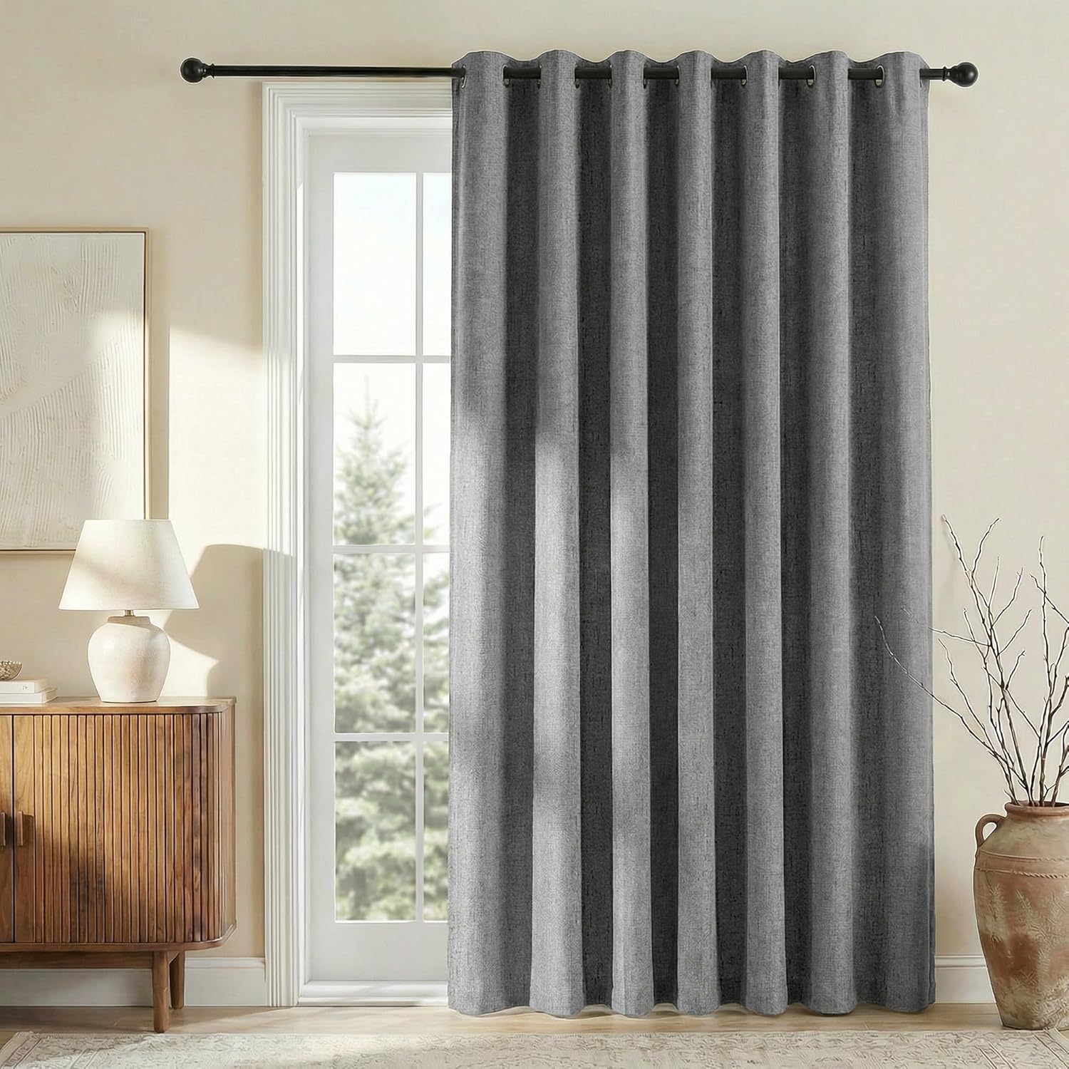 Textured charcoal grey grommet top curtain panel with soft folds hanging on a black rod over a door.