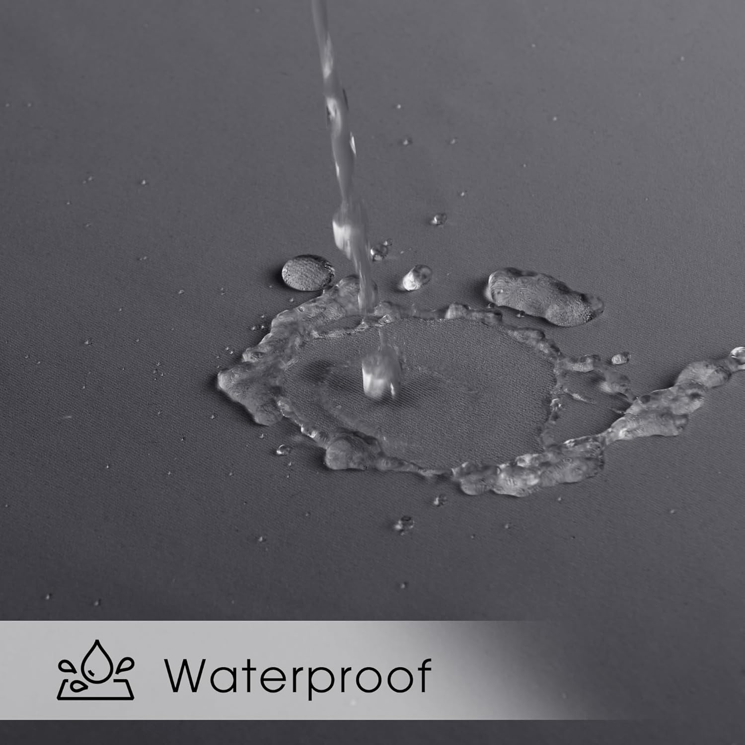 Close-up of water beading up on a dark grey waterproof fabric, demonstrating its water-resistant properties.