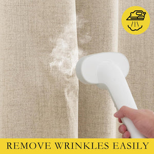 A hand uses a white portable steamer to remove wrinkles from a light beige textured linen curtain.
