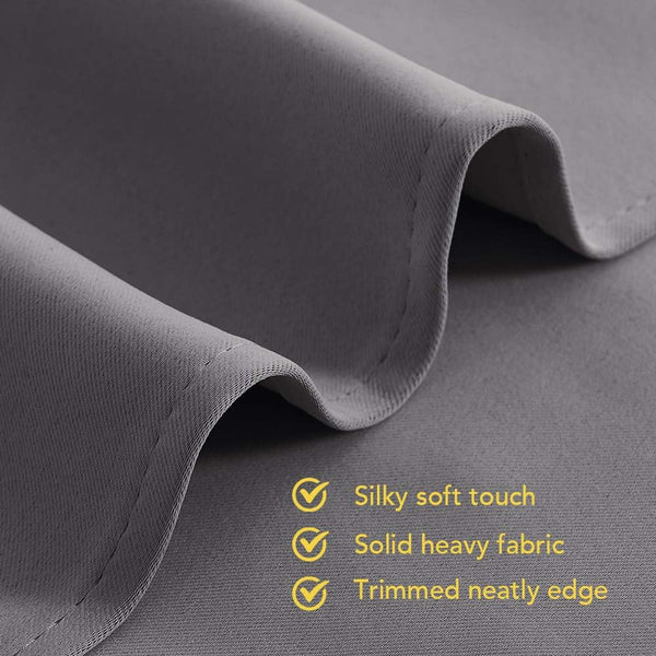 Close-up of a heavy, dark gray curtain fabric with a silky soft texture and neatly stitched, trimmed edge.