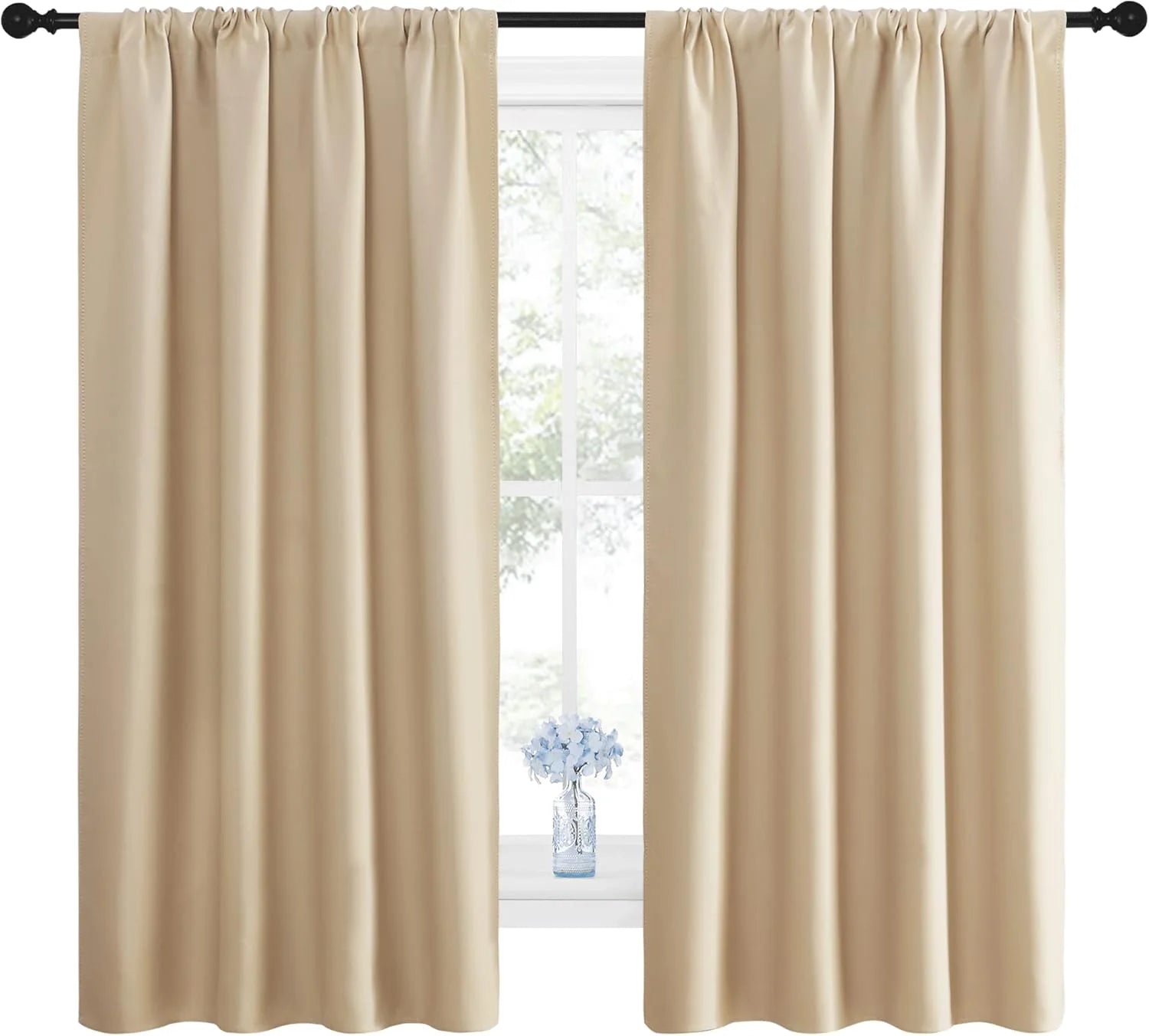 Ivory blackout curtain panels with soft pleats hanging on a black curtain rod