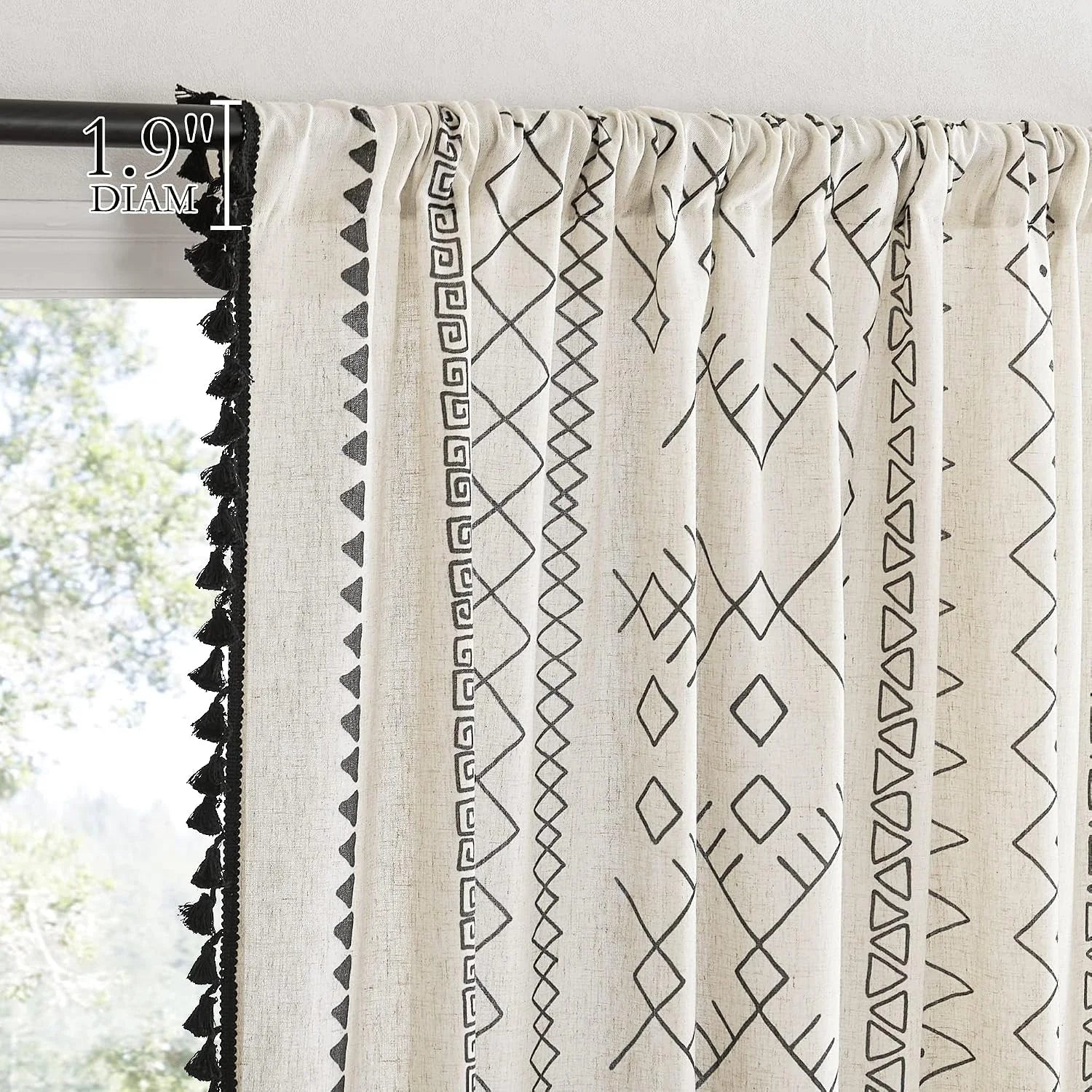 Ivory boho curtain with black geometric pattern and tassel trim on a black rod