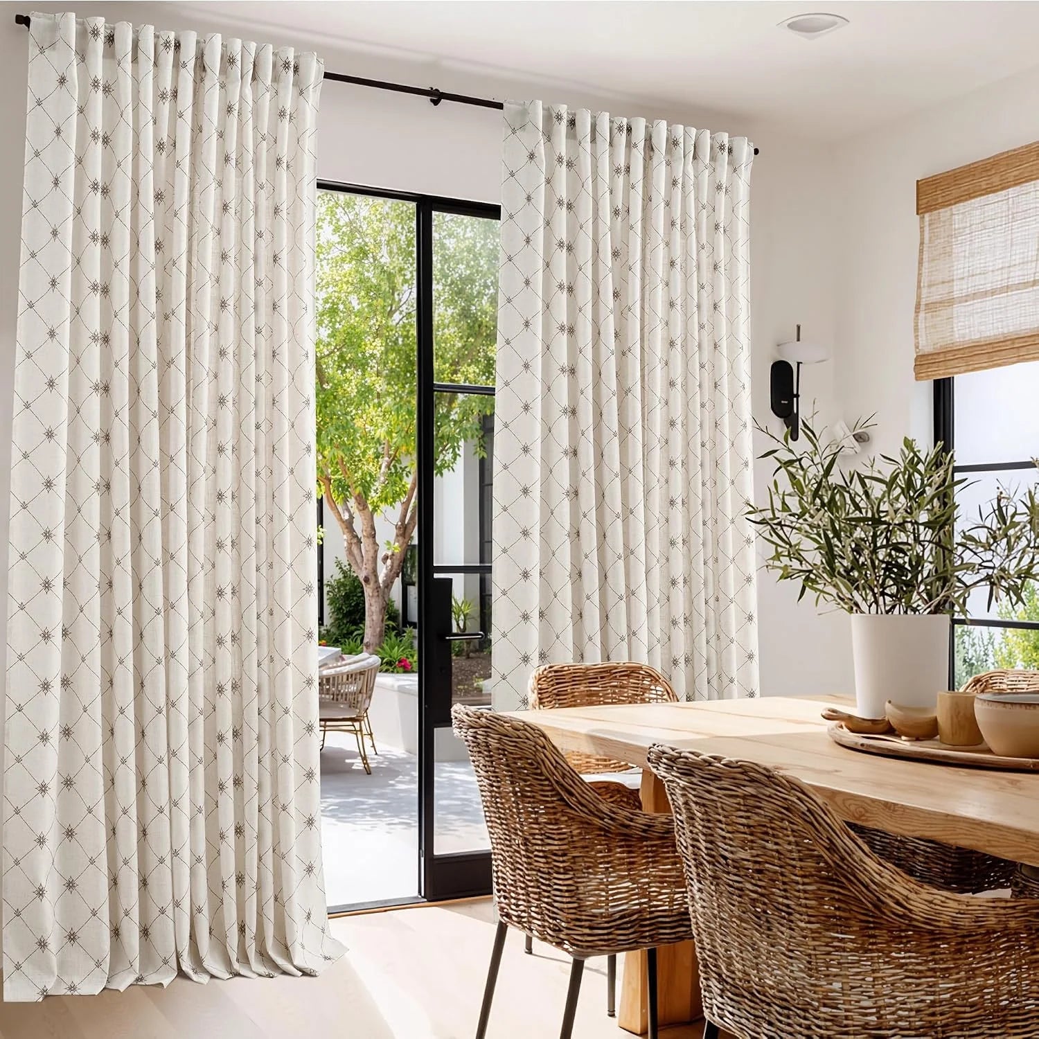 Ivory embroidered curtains hanging in a bright dining room with woven chairs