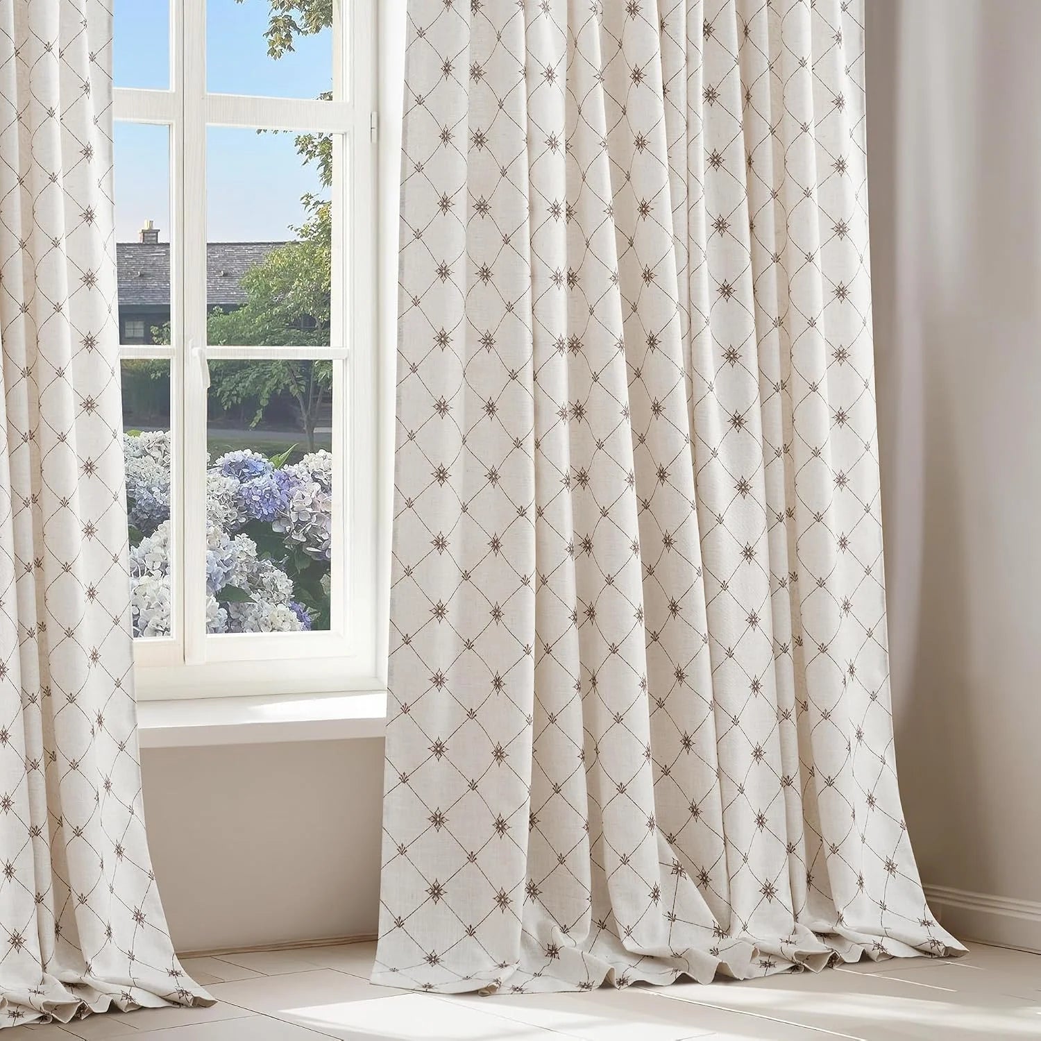 Ivory linen curtains with brown geometric embroidery beside a bright window
