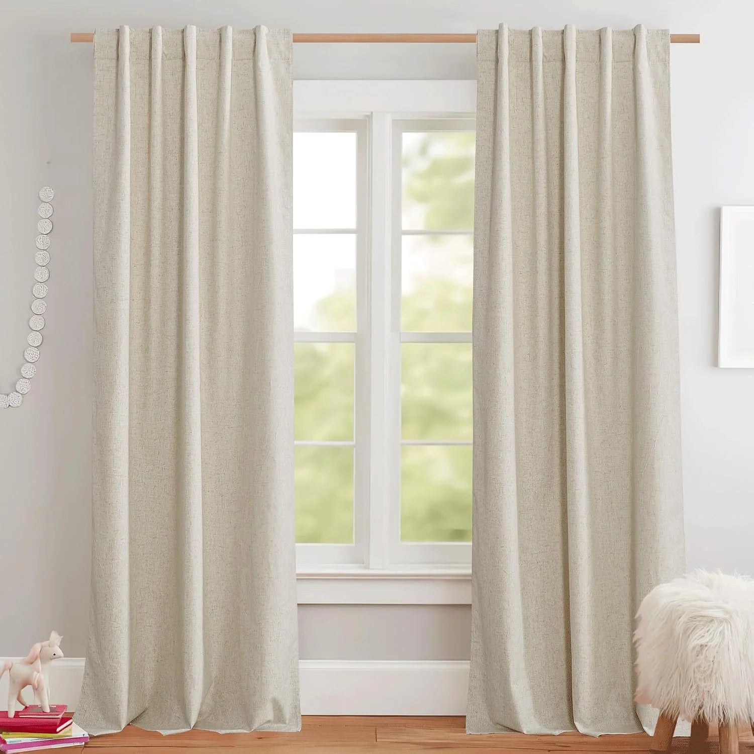 Ivory linen-look pleated curtains hanging on a wood rod over a bright window