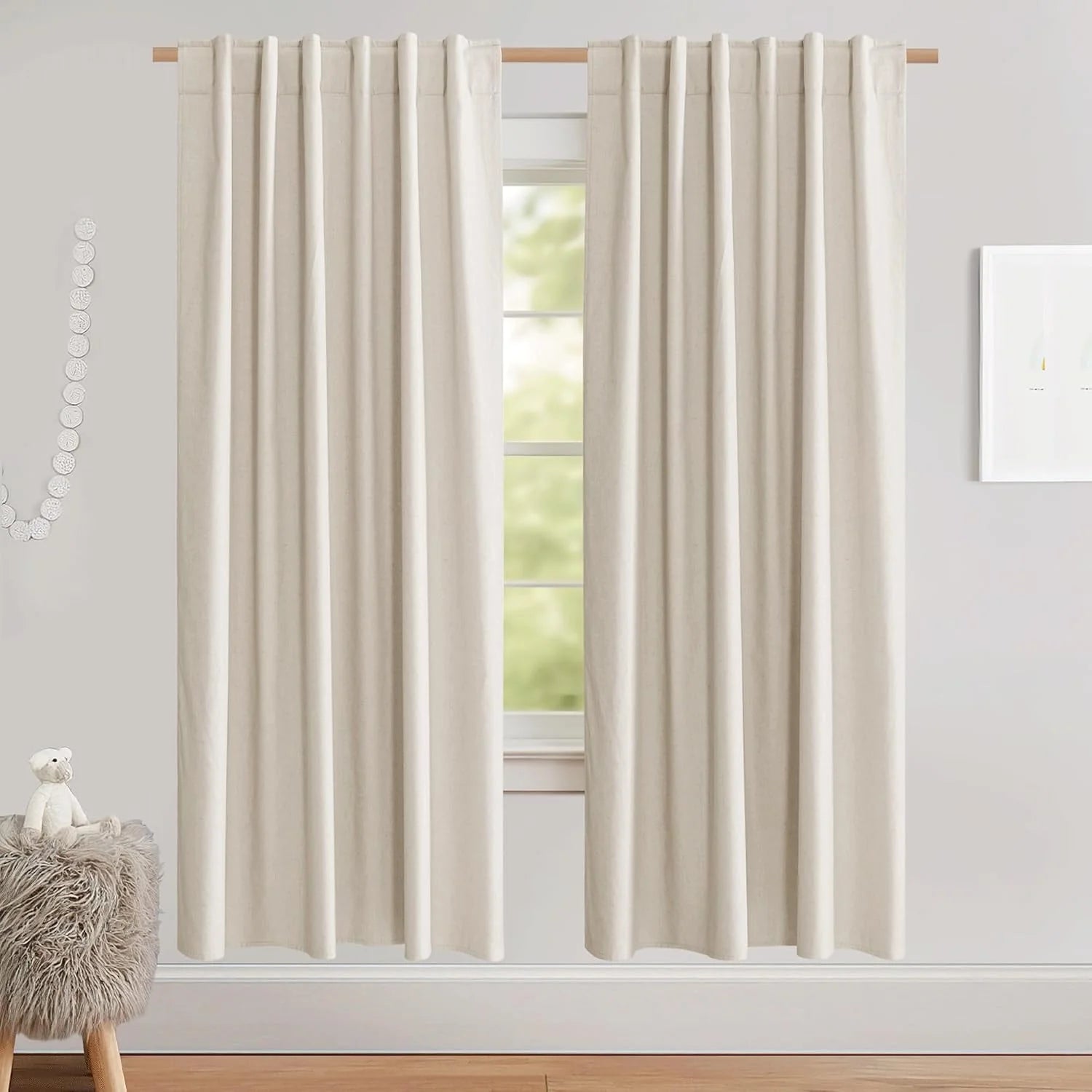 Ivory linen-look rod pocket curtains hanging in a soft neutral nursery room