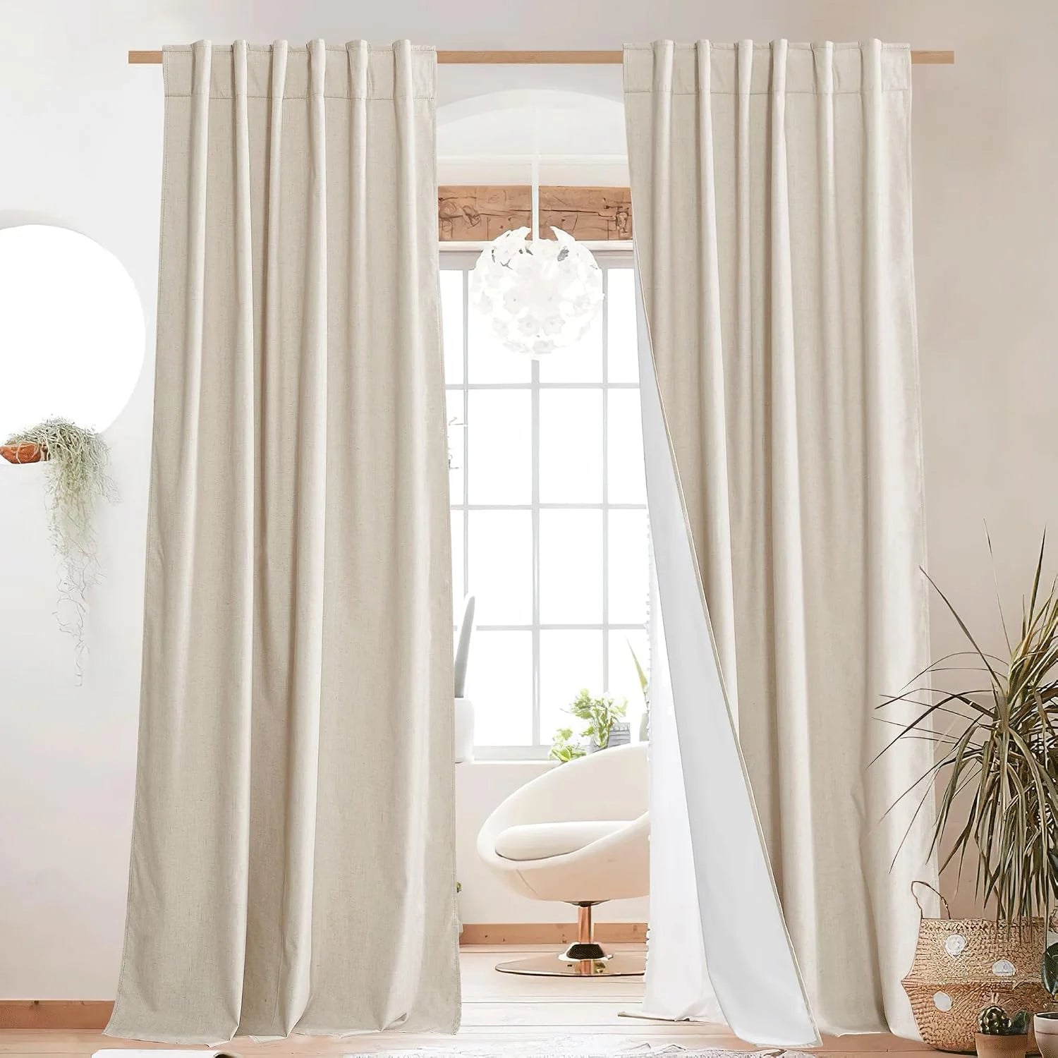 Ivory linen rod pocket curtains hanging on a wood pole in a bright modern room