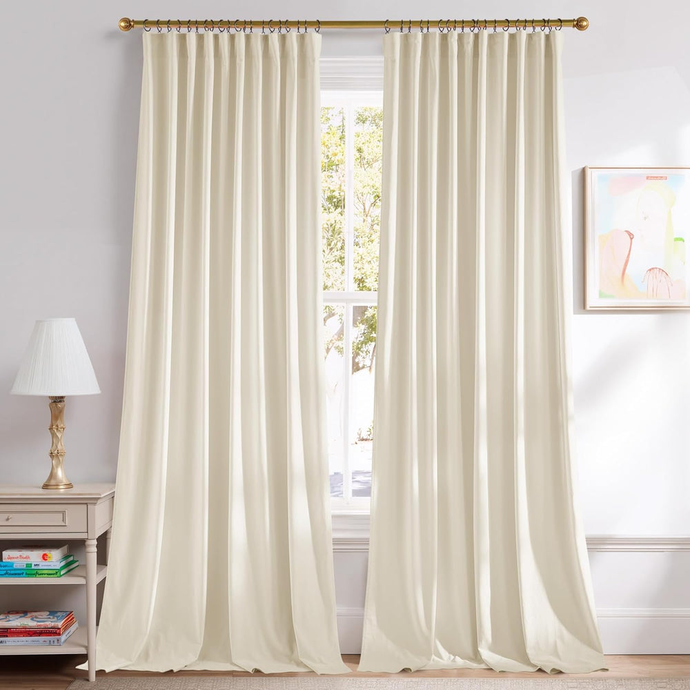 Pair of flowing ivory pleated curtains on a gold rod, covering a large window in a bright room.