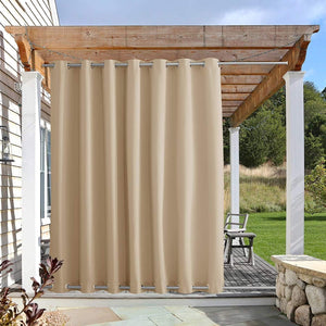 Khaki outdoor curtain with silver grommets hangs from a wooden pergola, providing privacy to an outdoor deck area.