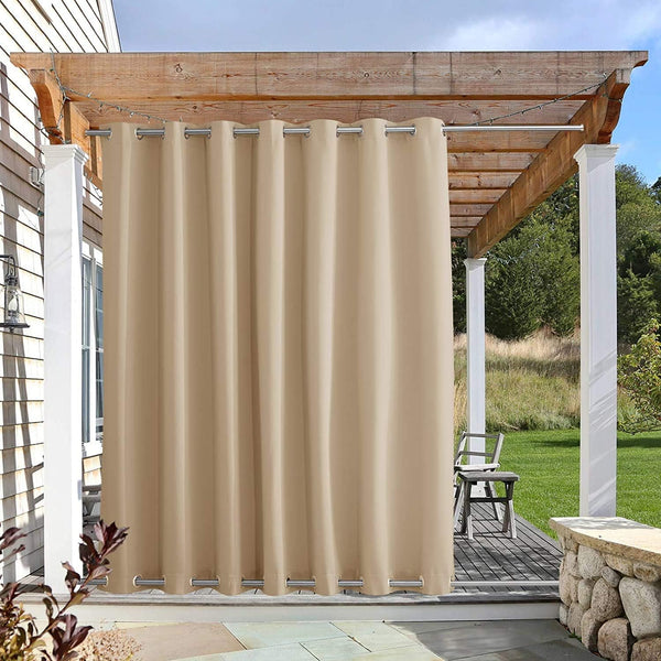 Khaki outdoor curtain with silver grommets hangs from a wooden pergola, providing privacy to an outdoor deck area.