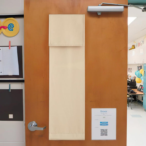 Light beige fabric door privacy shade with stitched edges, hanging on a wooden classroom door.
