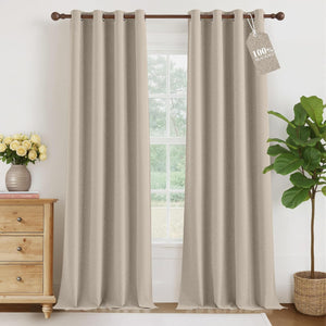 Light beige textured blackout curtains with grommet tops, hanging on a dark wooden rod in a bright room.
