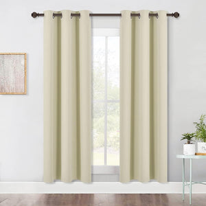 Light beige solid grommet top curtains hang on a dark rod over a window in a modern room.