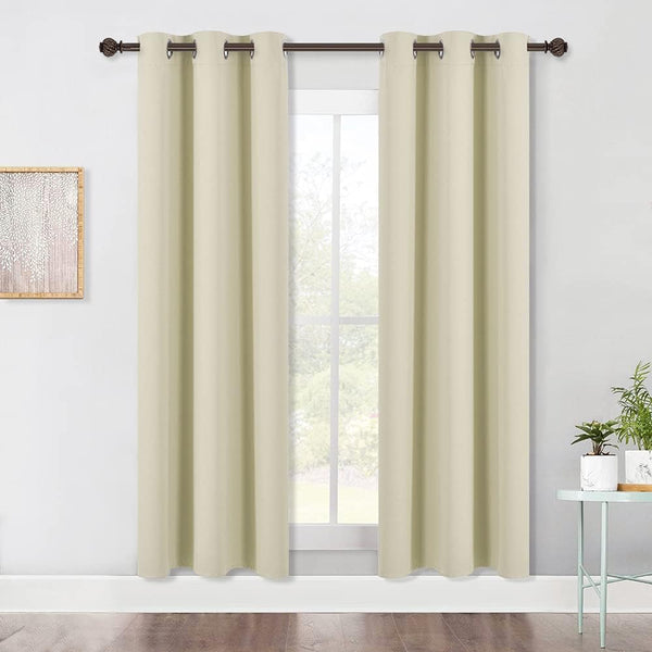 Light beige solid grommet top curtains hang on a dark rod over a window in a modern room.