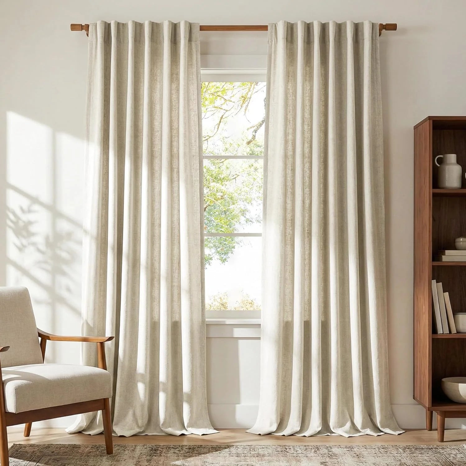 Light beige linen-look curtains on wooden rod in modern living room with neutral armchair.